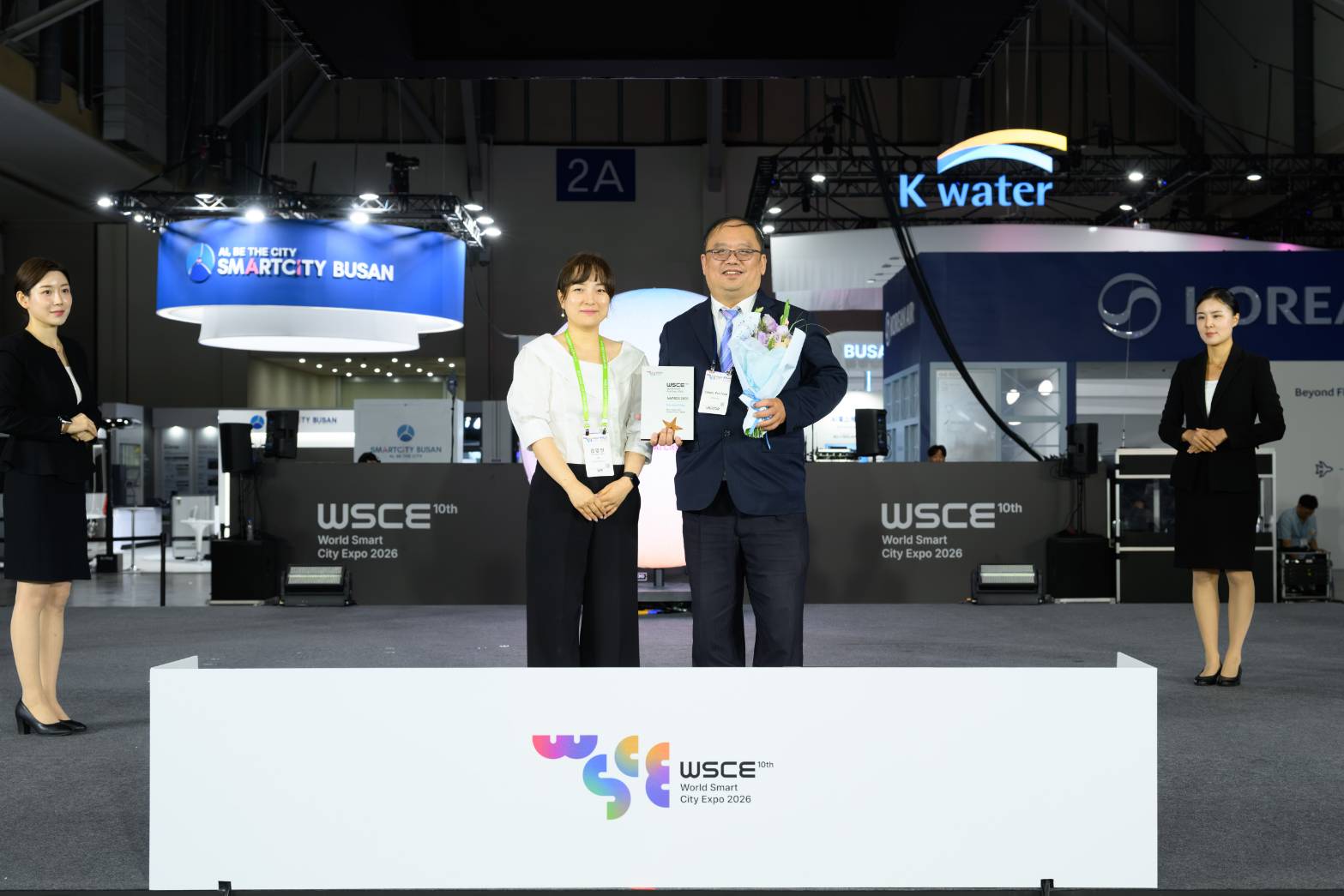 新北市政府出席韓國「WSCE+2026世界智慧城市博覽會暨頒獎典禮」，由世界智慧城市博覽會秘書長金伶仁(左)頒獎，資訊中心主任陳富添(右)代表領獎